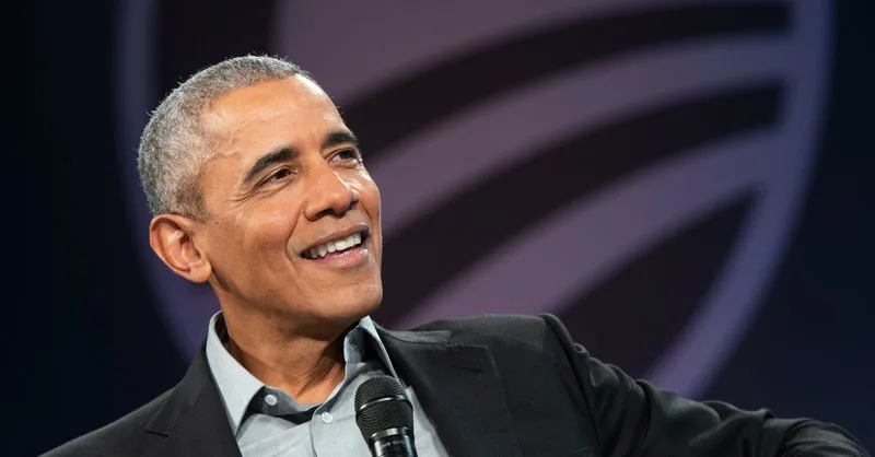 In this portrait, President Obama smiles looking off to the right while holding a microphone 