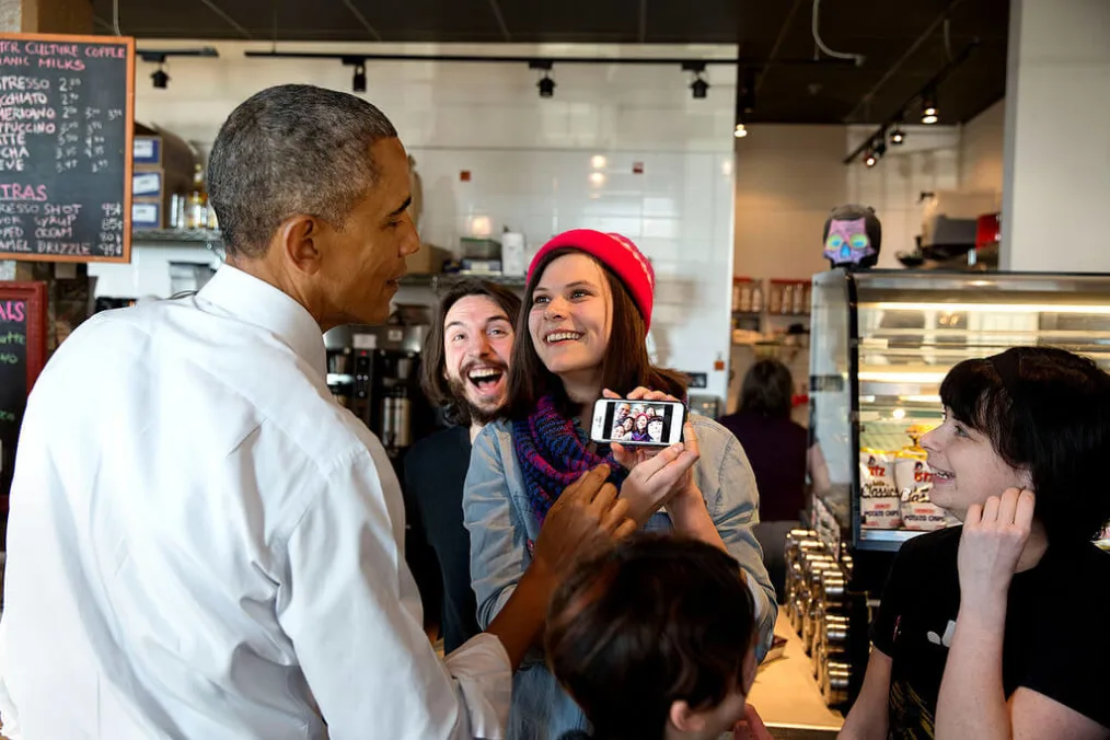 President Barack Obama looks at a selfie taken with restaurant staff