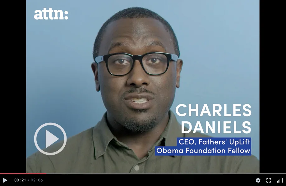 Charles Daniels, is a Black man with a deep skin tone with a buzz cut. He has glasses, a moustache and goatee with grey streaks, and a olive colored button up shirt. He is the CEO of Fathers' UpLift.