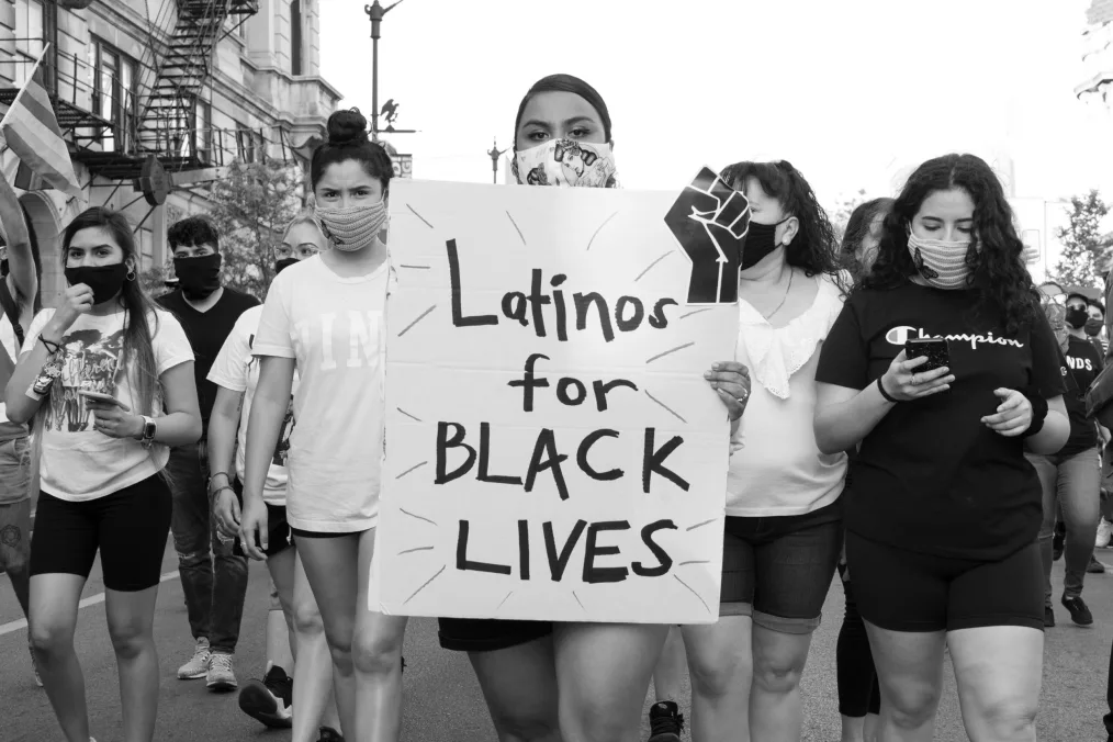 Young person carried 'Latinos for Black Lives' poster. 