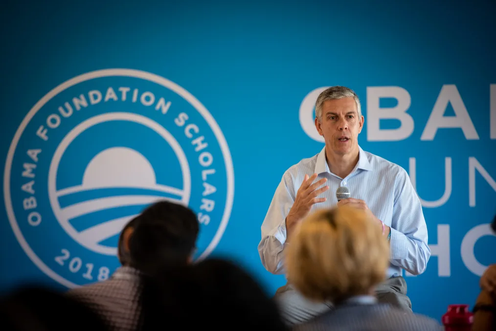 A man, Arne Duncan, addresses an audience in front of an Obama Foundation backdrop.