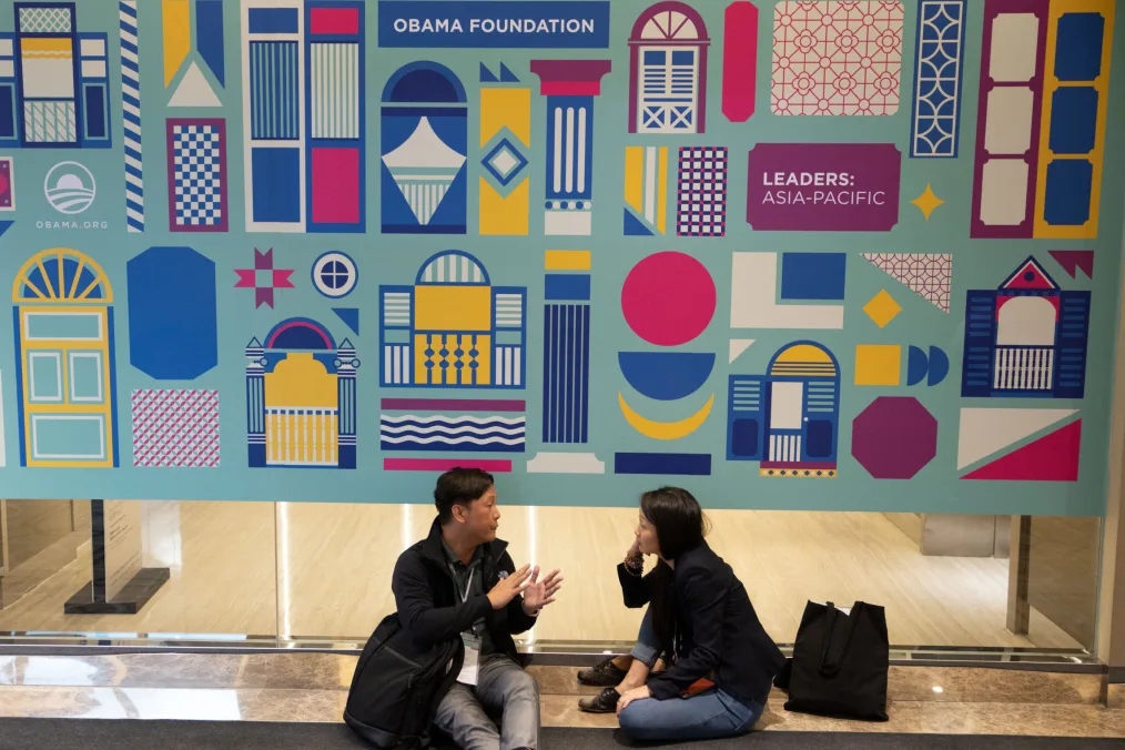 Two young Leaders sit under a banner designed by Valen Lim Chong Chin.