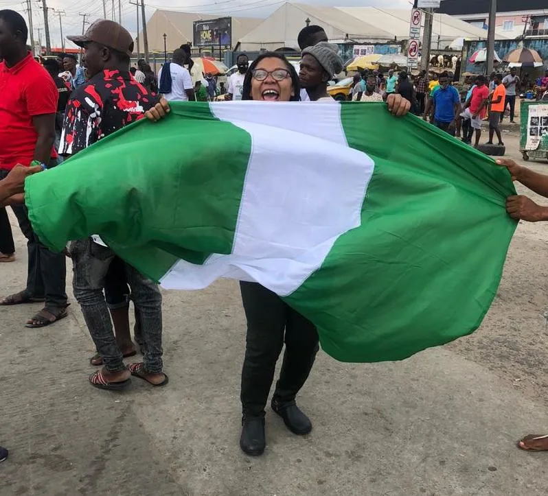 Isabella Akinseye smiles while waving a Nigerian flag.