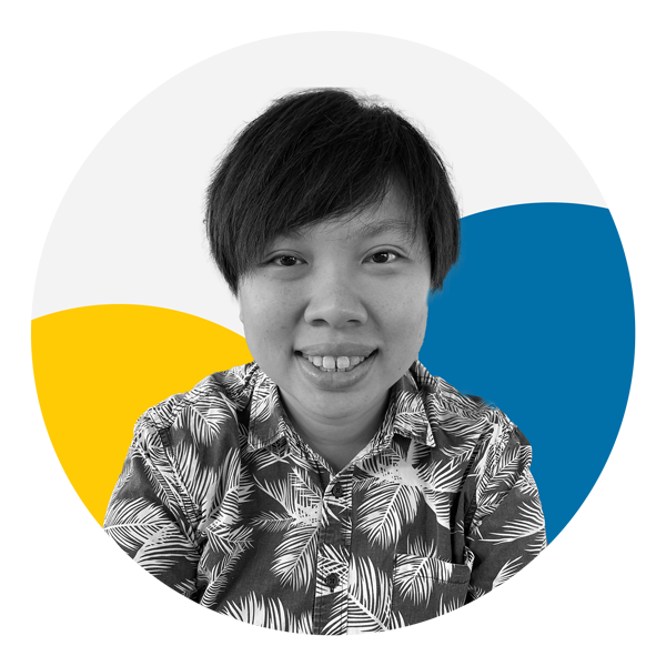 A medium skin toned person with short black hair is facing the camera smiling with their teeth showing. The person is wearing a patterned button-up shirt. The photo is black and white and the background features two circles, one which is yellow and the other blue. 