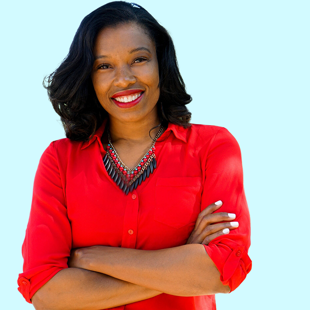 The image is a headshot of Jamila Thomas. Jamila has medium deep complexion, brown eyes, with a dark hair that falls to her shoulders. She is smiling in the photo. She is wearing a red button-down shirt with a pocket on the left side. She is wearing a beaded tribal necklace that has red, turquoise, and black beads. Her arms are folded across her chest. She has white nail polish on her fingernails. The background of Jamila's image is the color light blue.
