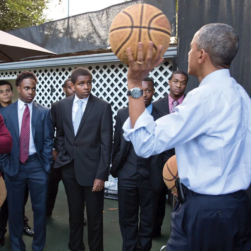 Holding a basketball, President Obama faces a group of young men during a My Brother's Keeper meeting.