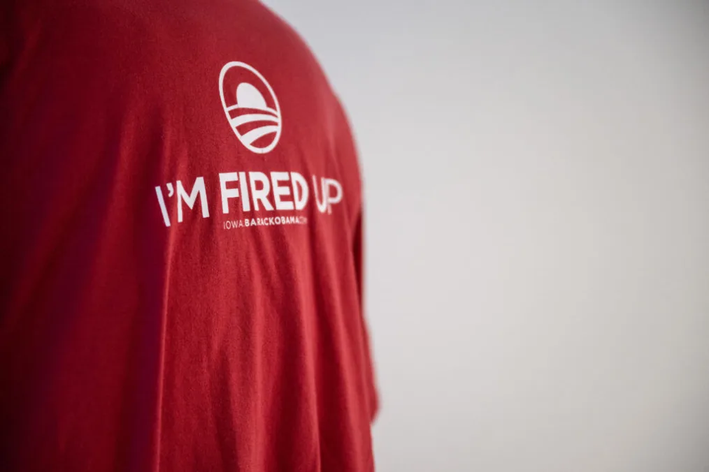 A red t-shirt is shown in profile on the left side of the image. “I’m fired up” is across the chest in white text, with the white rising sun logo above it.