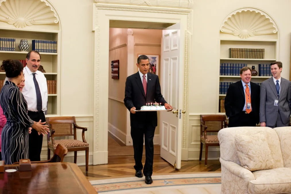 President Barrack Obama carries a cake into the Oval Office