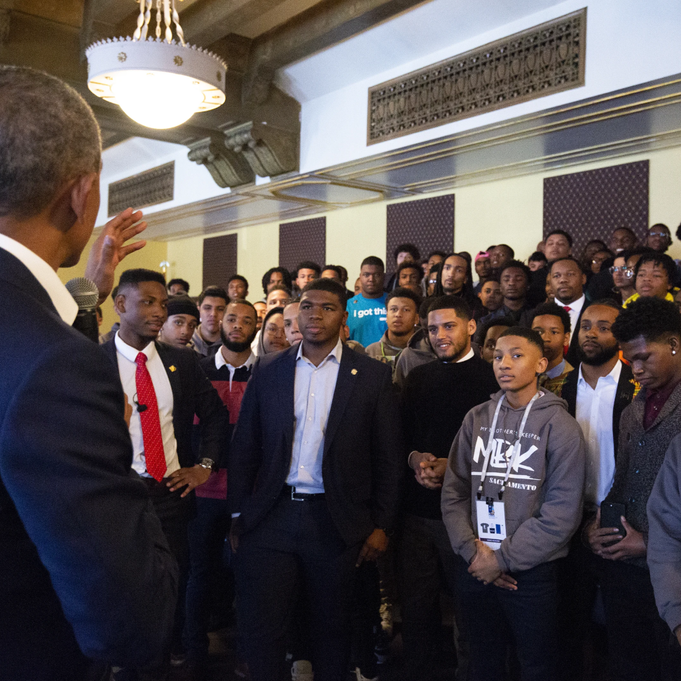 President Obama speaks to a group of young black men of various skin tones.