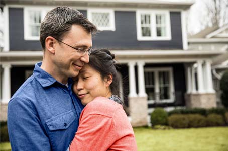 Couple hugging in front of house.  Size of image 454 X 300 px.