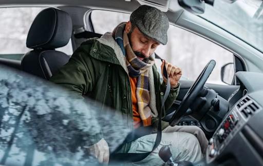 Man i bil som knäpper sitt bilbälte. 