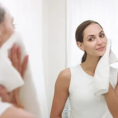Young woman using facial cleaner