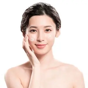 Young woman treating facial skin with care containing ceramides