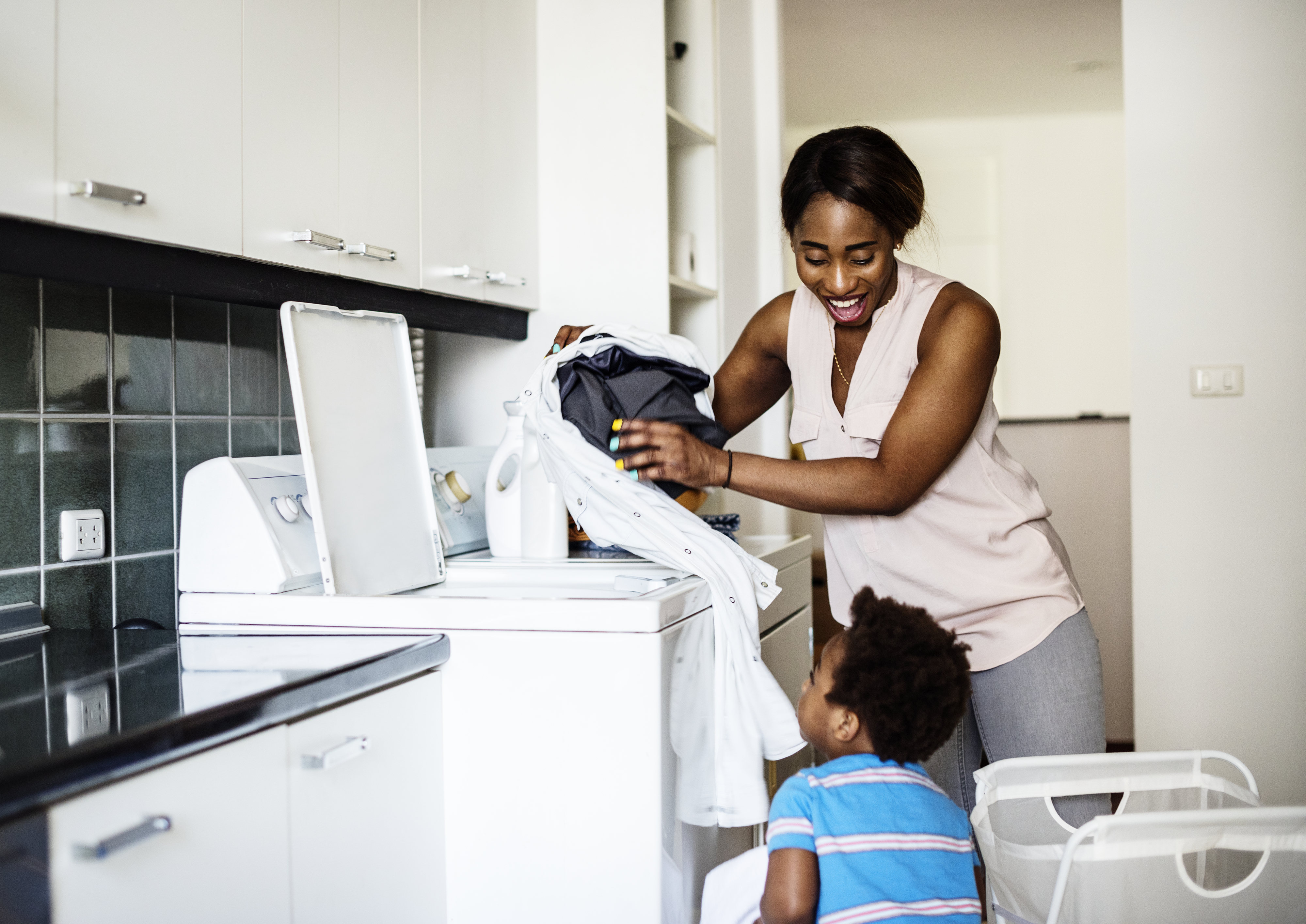 Woman loads washing machine while smiling at her son