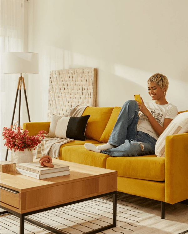 A woman sits on a couch using her phone 