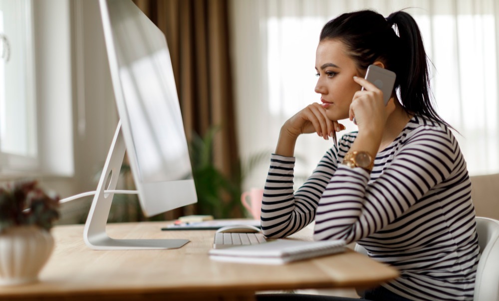 A woman on the phone sits in front of a monitor