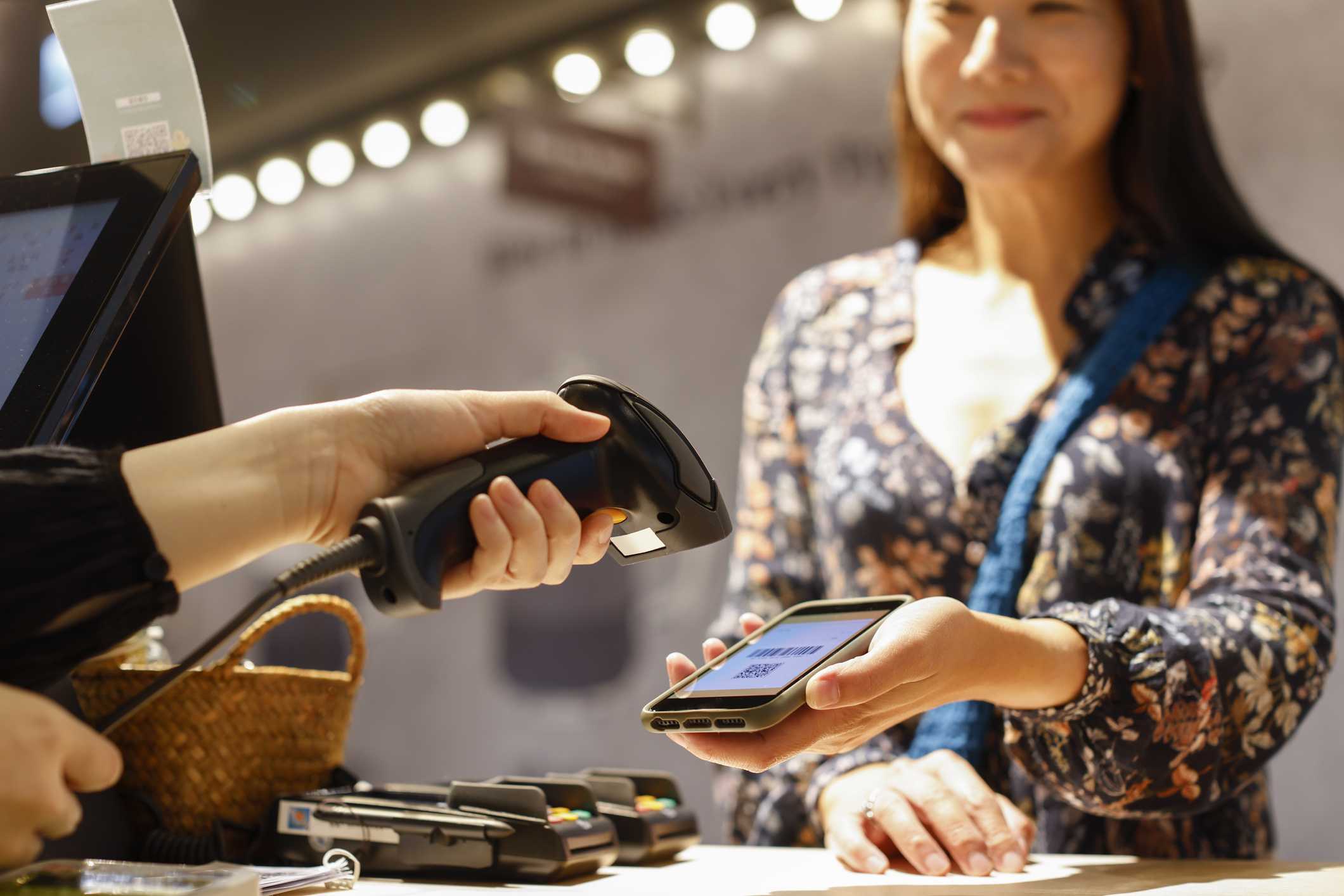 A woman shows her phone to a cashier so they can scan her barcode and qr code. 