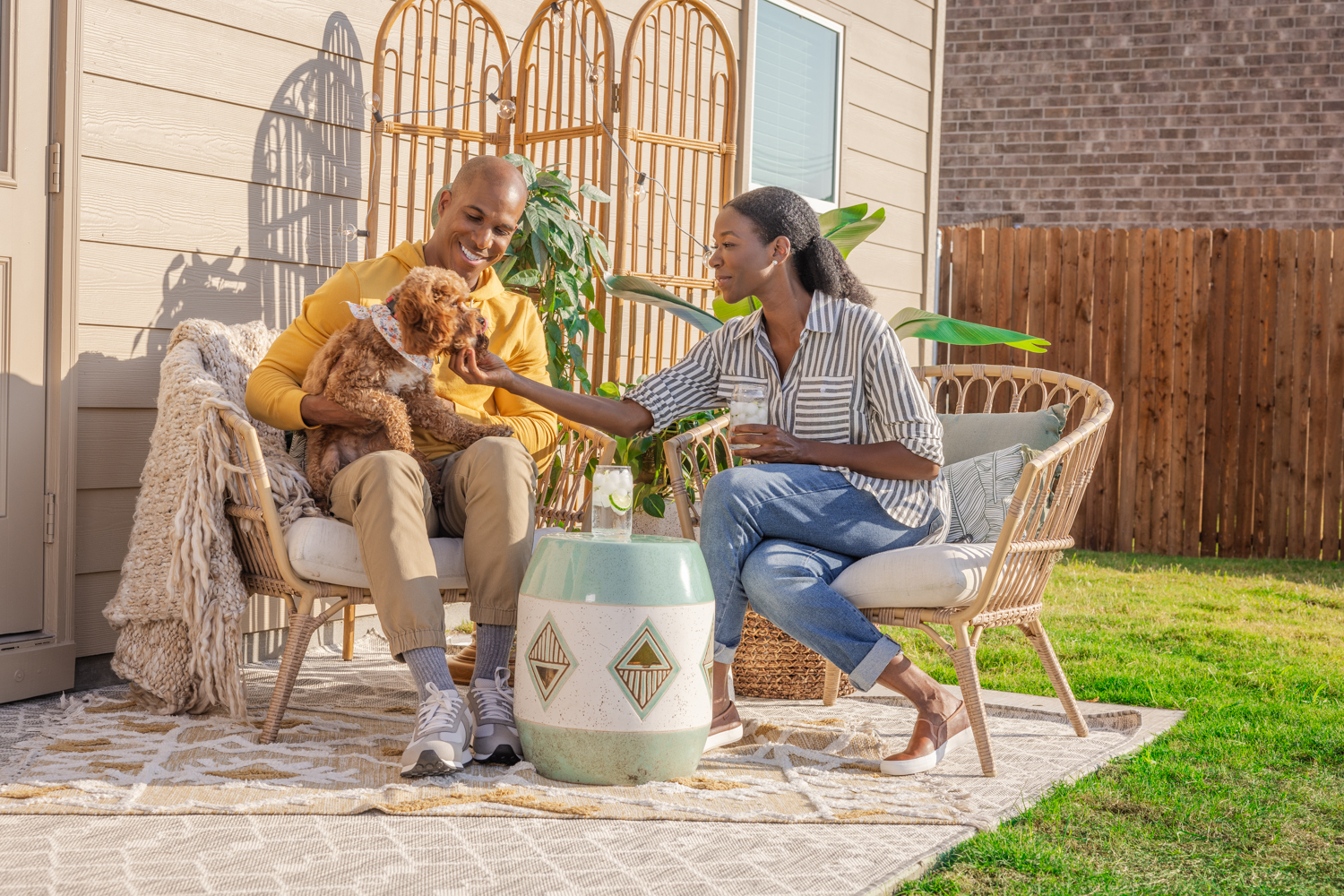 A couple sitting on their patio and petting their dog