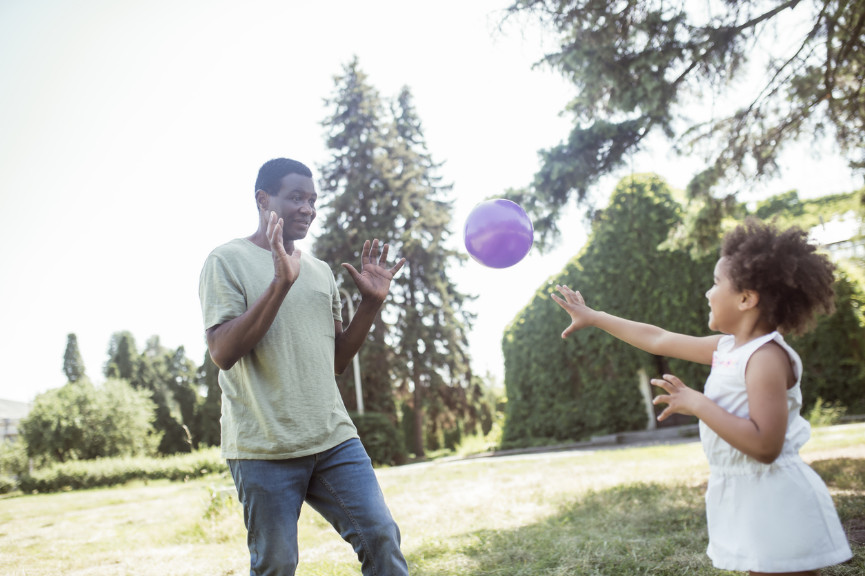 A man and a girl play with a ball