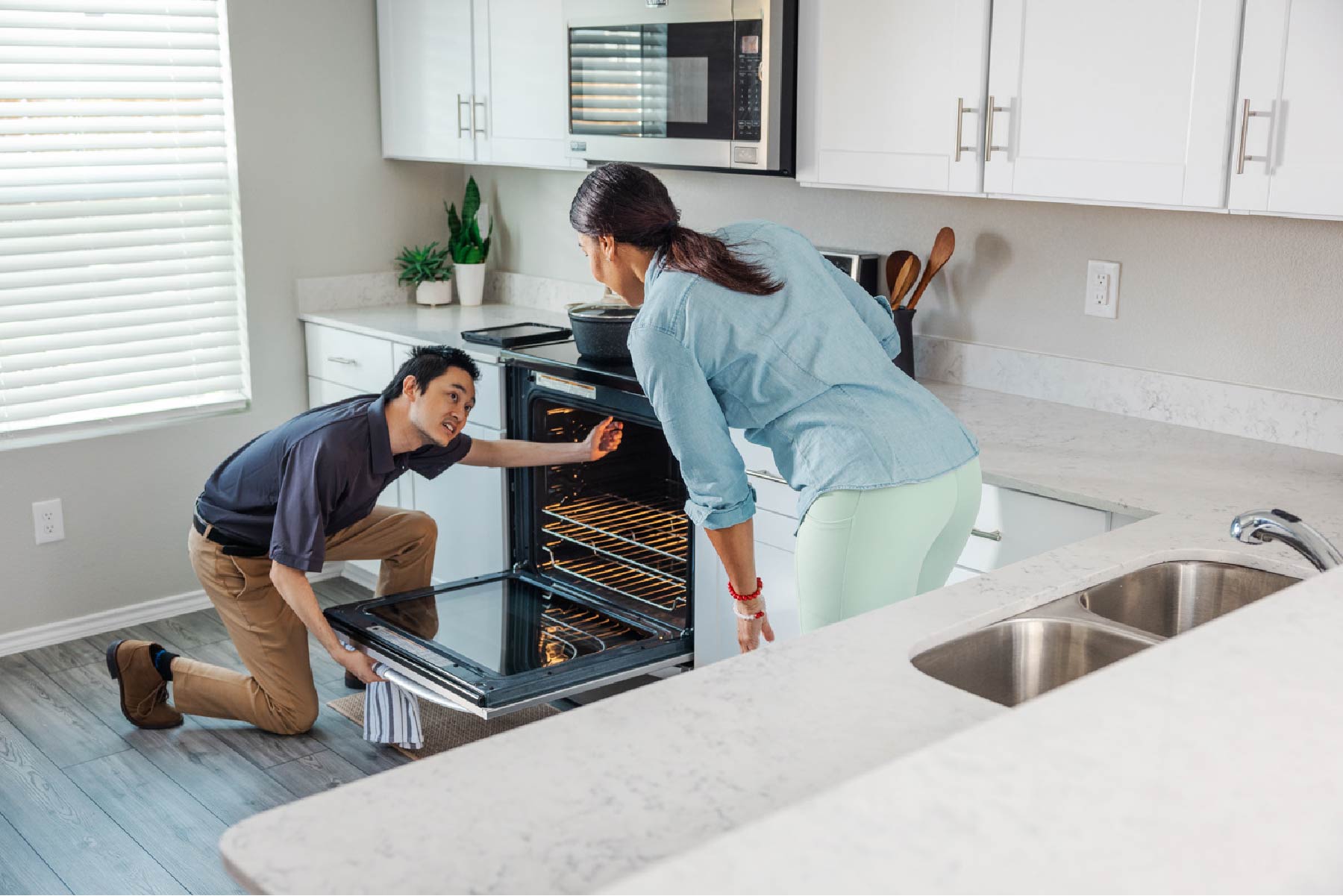 Invitation Homes associate helps resident with oven.