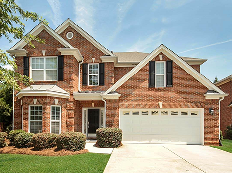 two story red brick house with a two car white garage