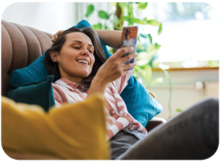 Woman sitting on the couch smiling which checking her phone.