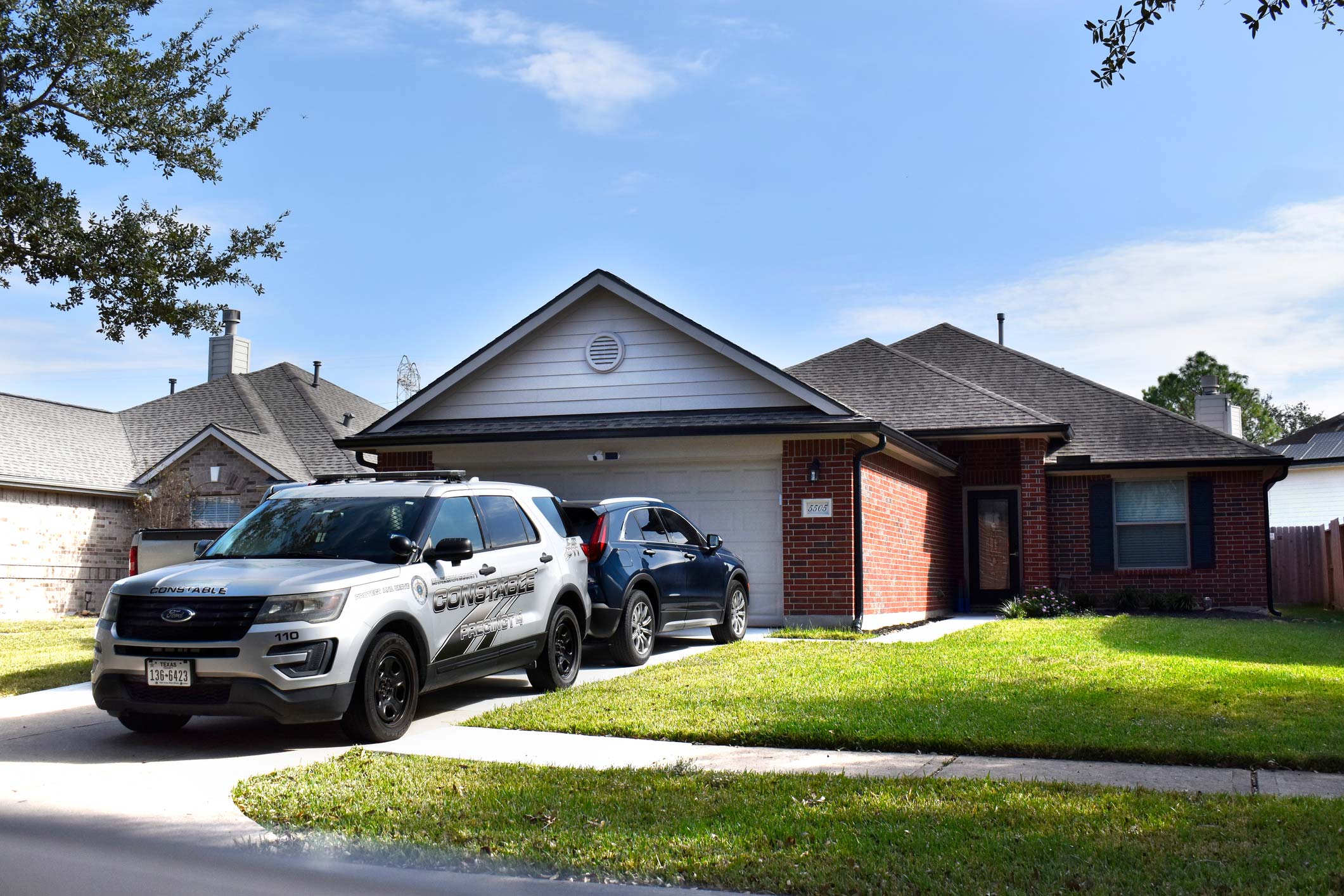 A police car parked in the driveway of a single family home.