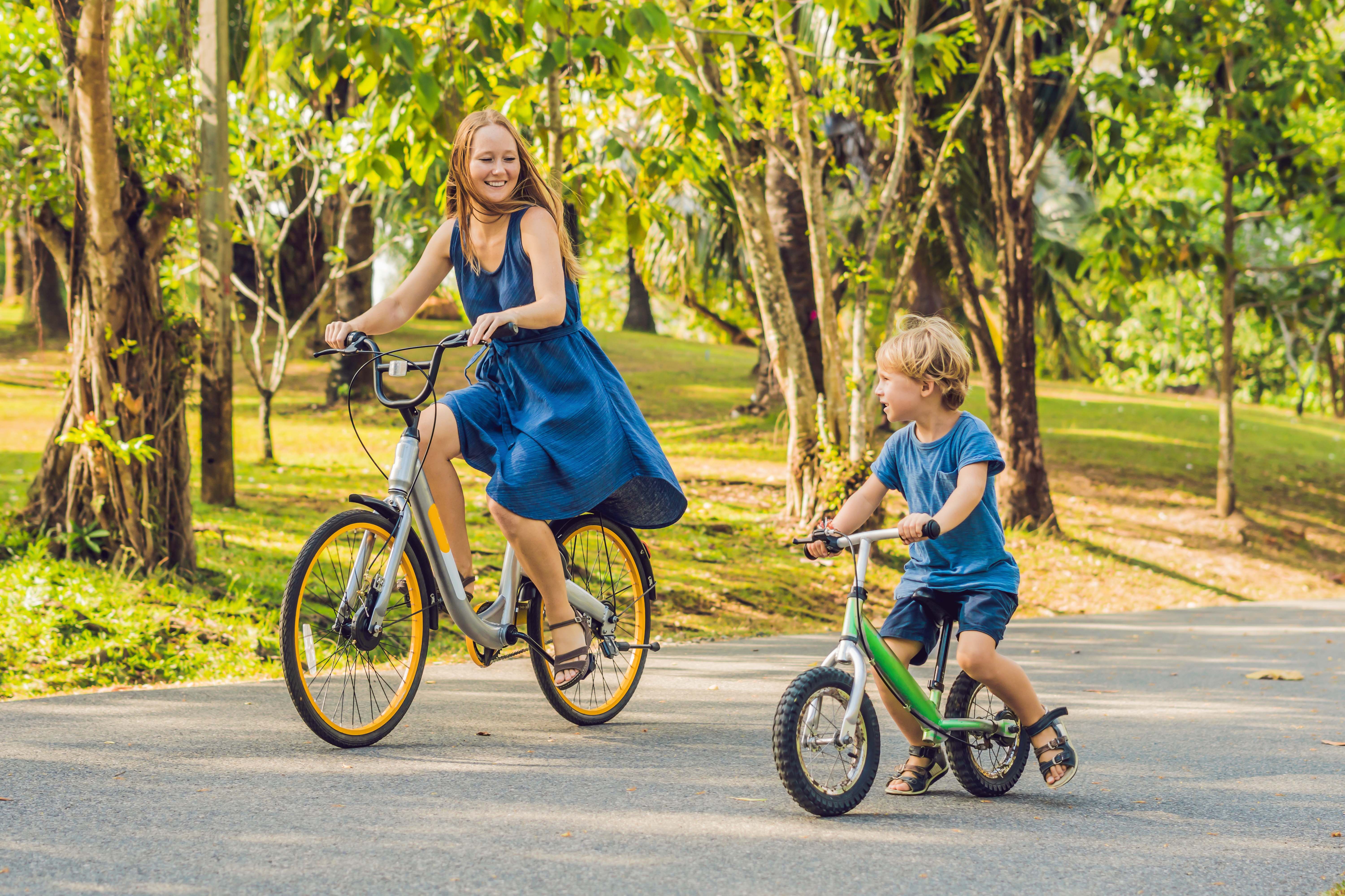 woman and little boy riding bikes down a paved road