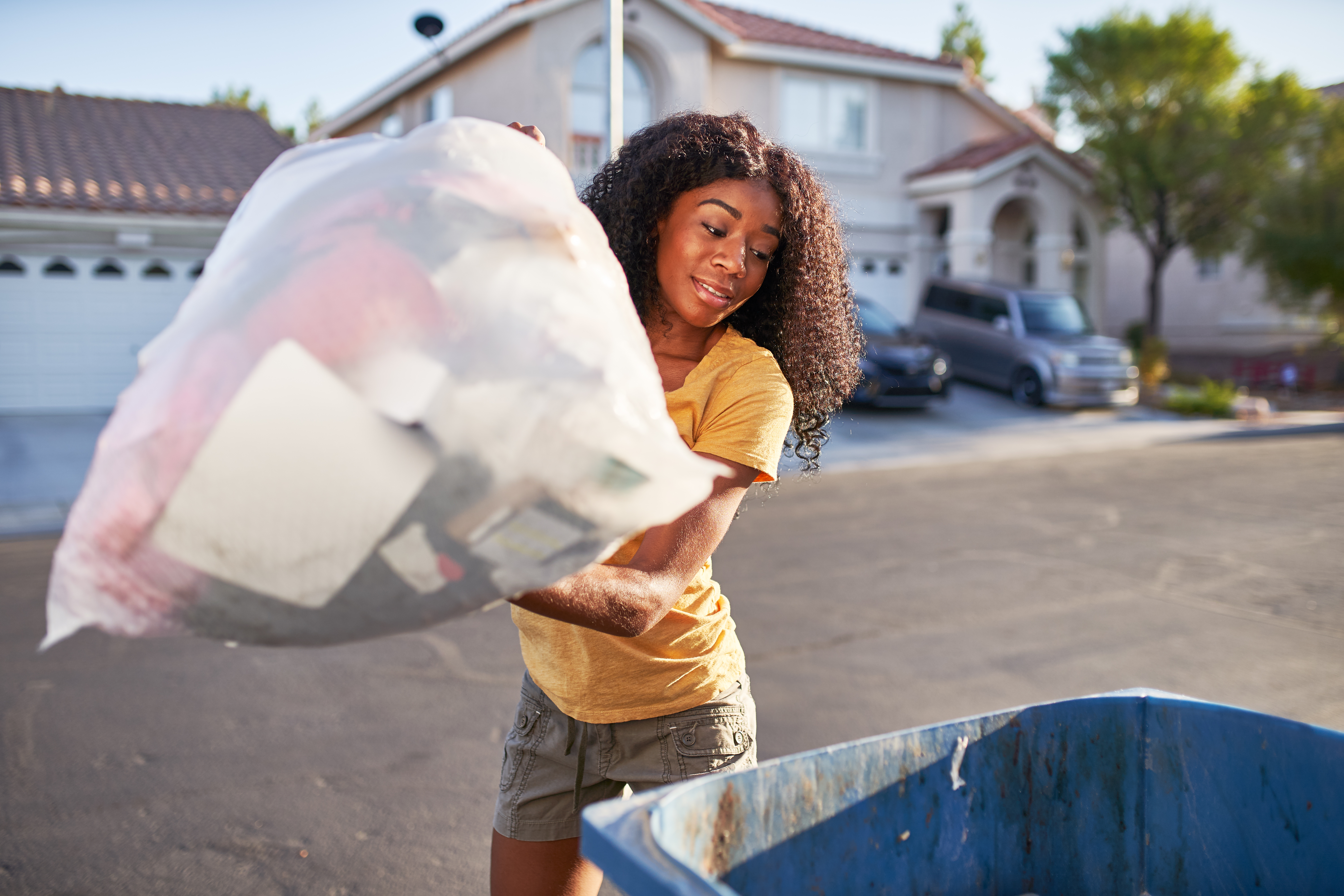 Young woman taking out the trash.