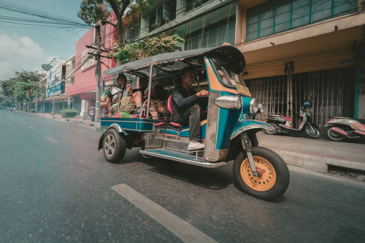 https:A vibrant image of Bangkok showcasing top attractions such as the Grand Palace, Wat Arun, bustling street markets, and a view of the Chao Phraya River with traditional boats.