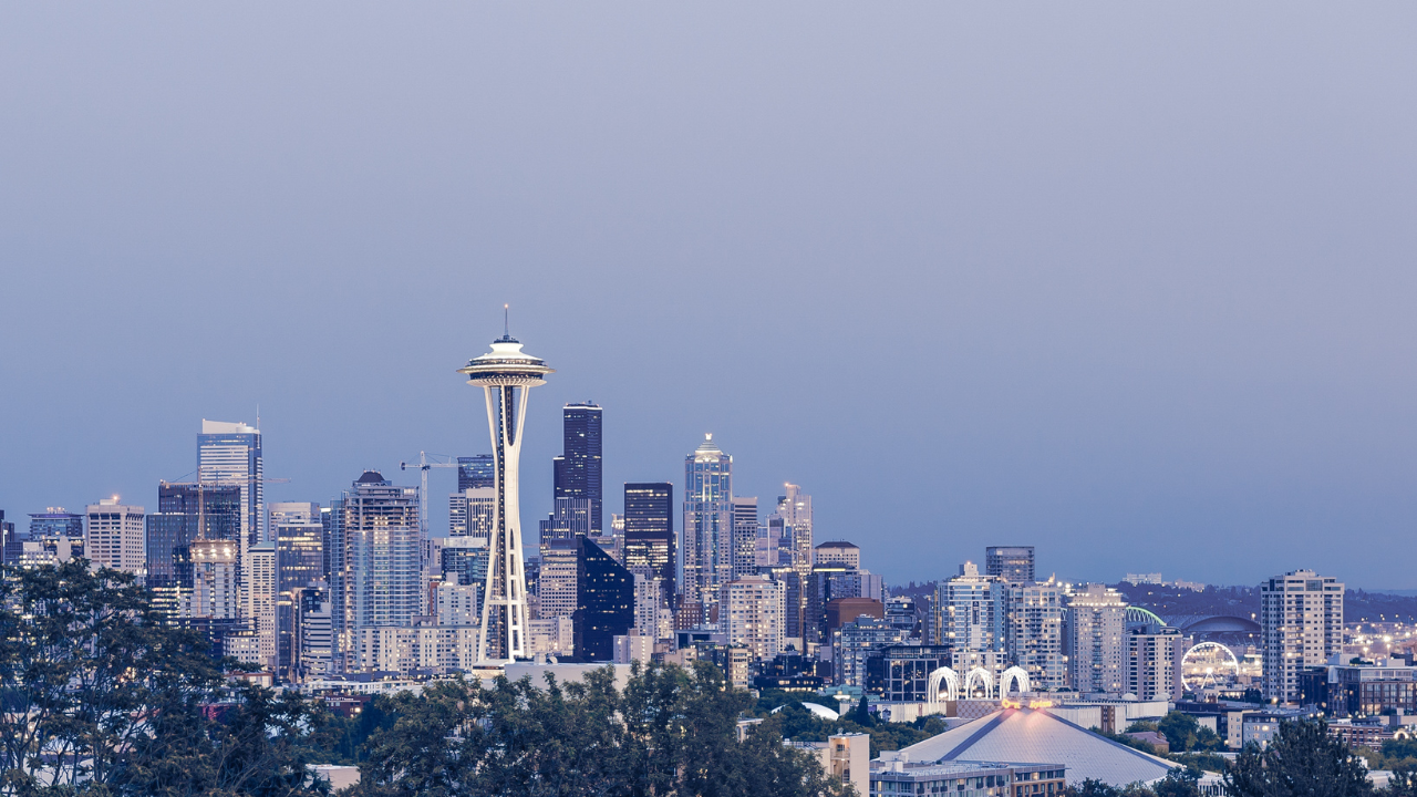 https:Photo of Seattle's skyline featuring the Space Needle and iconic skyscrapers with majestic Mount Rainier in the distance. 