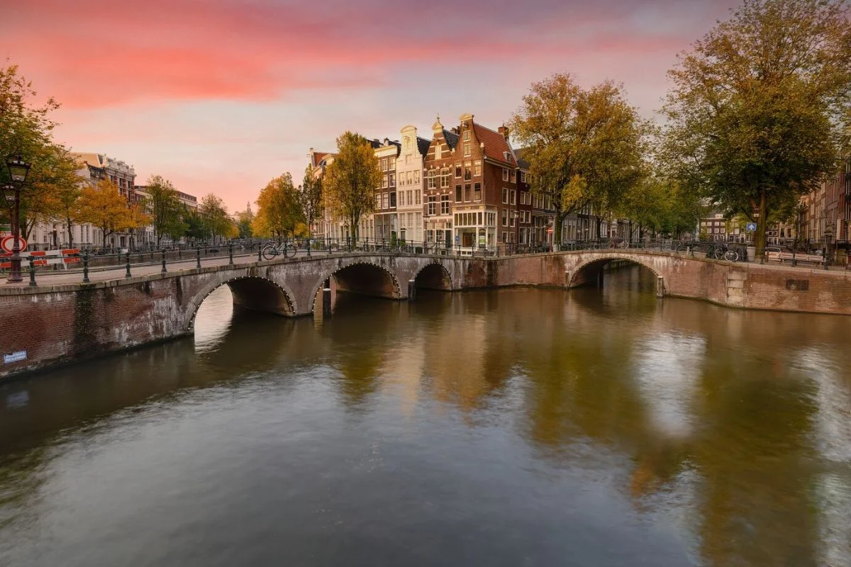 Amsterdam’s canals lined with trees in brilliant fall colors, making it a top autumn destination in Europe.