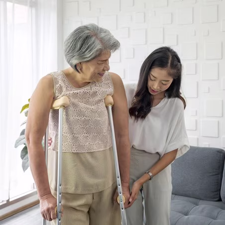 Young Asian woman help her grandma walk by using axilla crutches