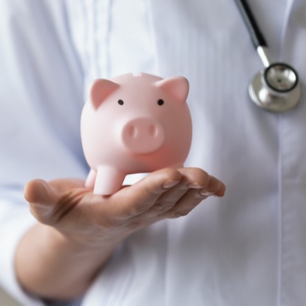 Woman doctor holding piggy bank box