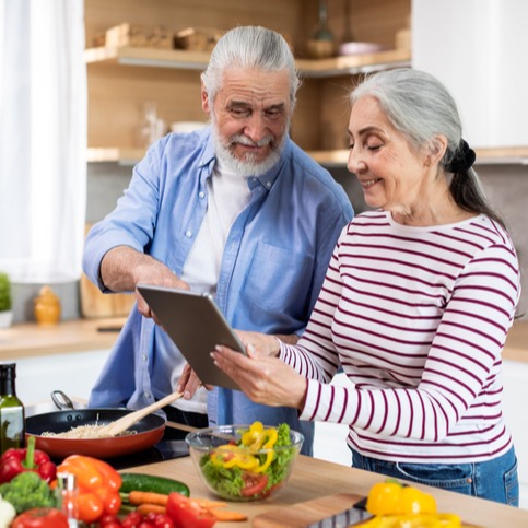 Happy Senior Couple Using Digital Tablet In Kitchen
