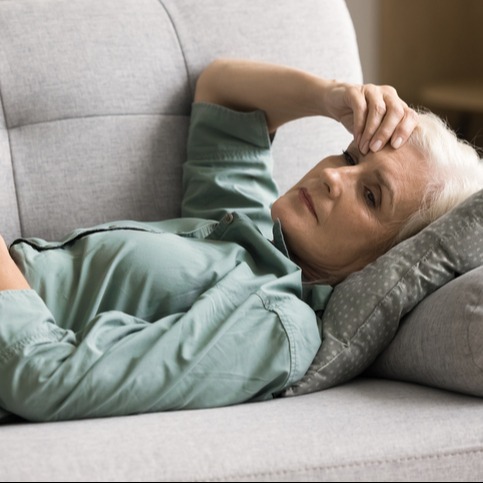 Mature Woman Resting on Sofa Due to Qulipta-Induced Vertigo and Fatigue