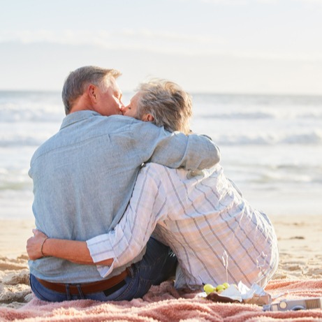 Senior couple, beach picnic and kiss with hug
