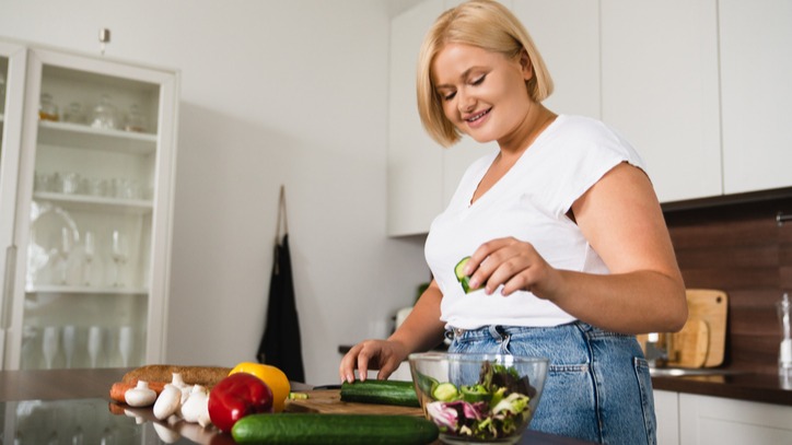 Woman plump plus size woman cooking making salad, healthy food, dieting, counting calories, preparing dinner lunch at home kitchen