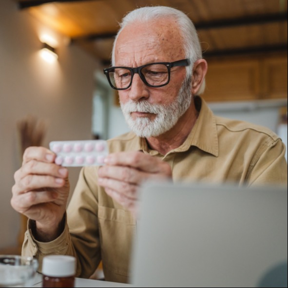 Older Man Reviewing Eliquis Tablet and Learning About Side Effects