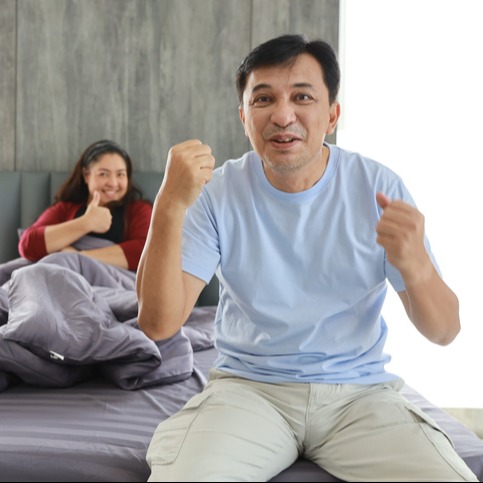 Happy middle aged Asian man sit on bed after having sex 