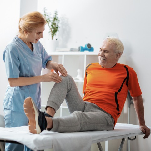 Pleasant senior man having a knee massage