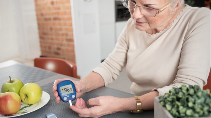 Senior woman checking blood sugar level at home