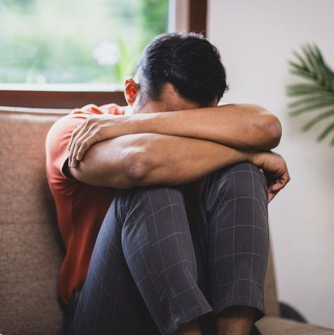 A man sitting on a sofa at home is sad, disappointed and upset.