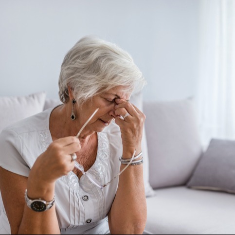 Tired elderly woman with mild headache at home