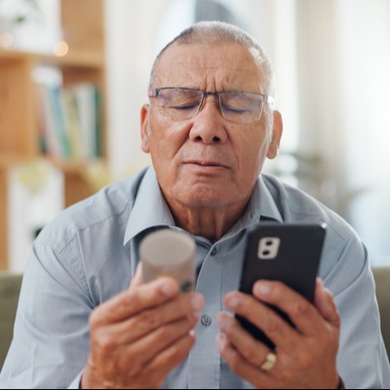 An elderly man reads the label of methenamine hippurate in a telehealth consultation.