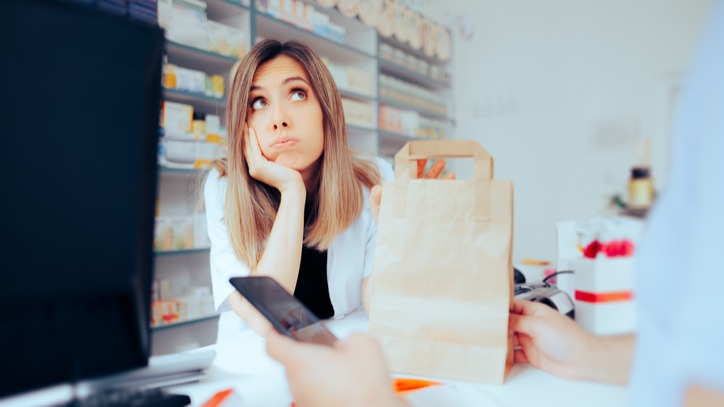 Tired Pharmacist Waiting for the Client to Make the Purchase