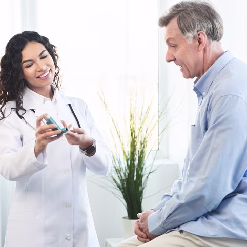 Physician showing mature man blue asthma inhaler