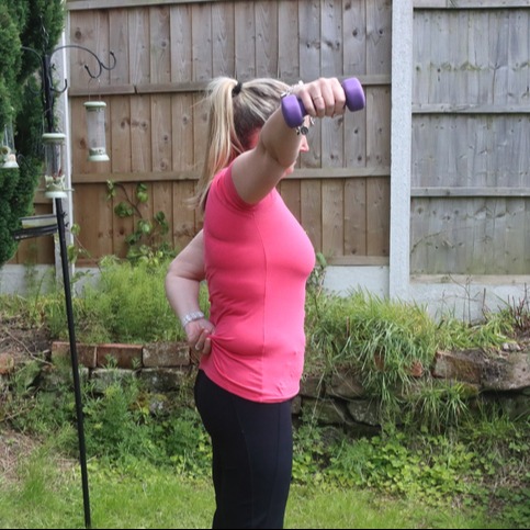 A photo of a middle-aged woman doing a mix of aerobic and anaerobic exercises in her backyard.