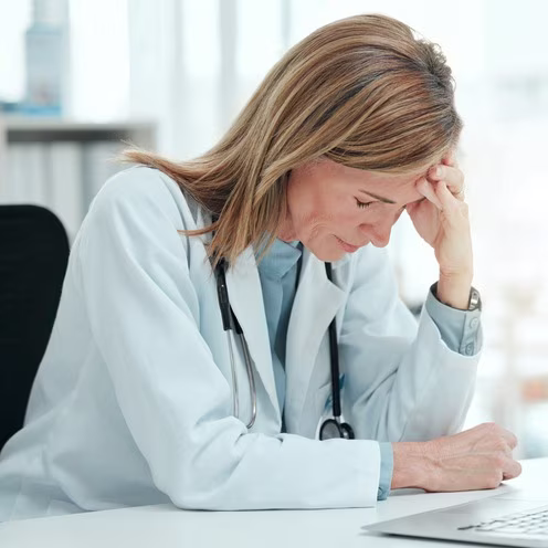 Mature doctor sitting alone in her clinic and feeling stressed