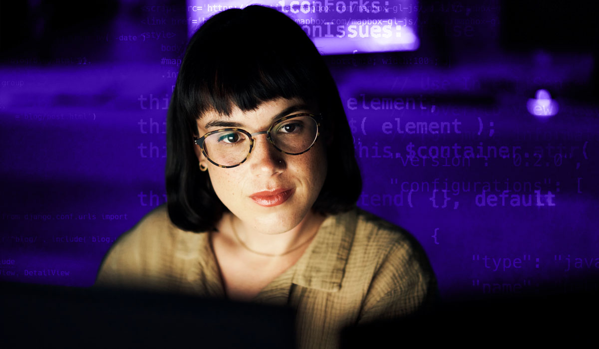 A developer at a desk coding surrounded by a background of lines of code.